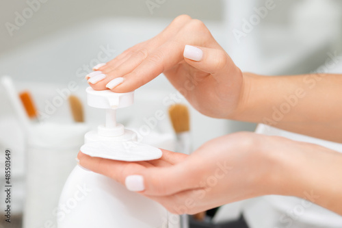A woman squeezes a cosmetic onto a cotton pad. Beautiful female fingers with manicure. Concept of skin care