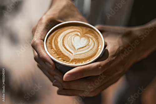 Man holding coffee cup with latte art,