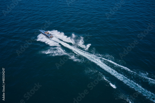Dark gray blue boat in motion at sea. Boat performance drone view. Performance speedboat moving fast on blue water aerial view. © Berg