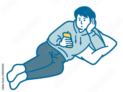 A man lying down and looking at a smartphone