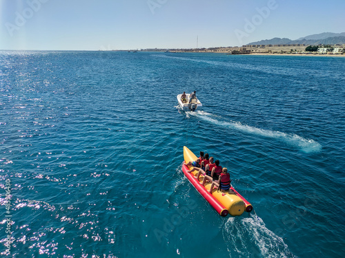 Hurghada, Egypt - October 1, 2021: People sit on the water attraction banana boat and ride on the red sea.