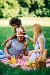 Happy multiethnic family enjoying picnic in nature