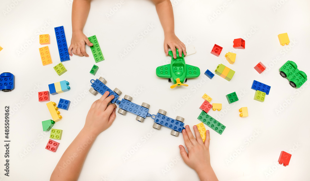 Close up kid boy hands playing with toy bricks on white background. Close up kid boy hands playing with toy bricks on white background.