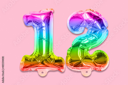 Rainbow foil balloon number, digit twelve on a pink background. Birthday greeting card with inscription 12. Top view. Numerical digit. Celebration event, template.