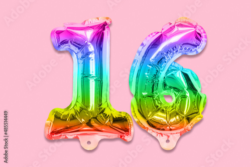 Rainbow foil balloon number  digit sixteen on a pink background. Birthday greeting card with inscription 16. Top view. Numerical digit. Celebration event  template.