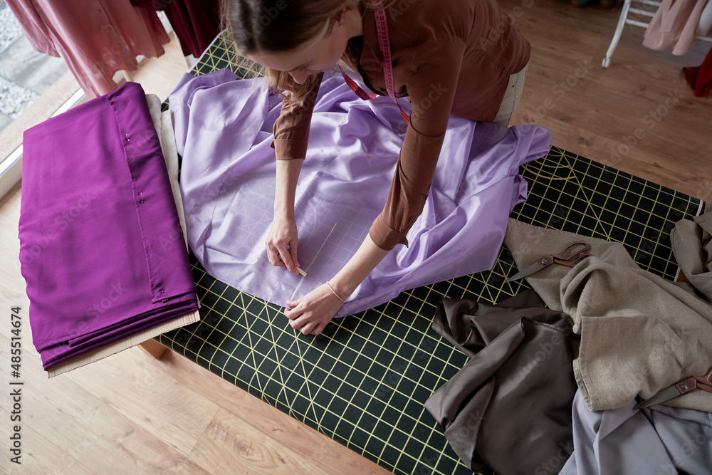 Obraz premium Caucasian tailor cuts out the template on the table