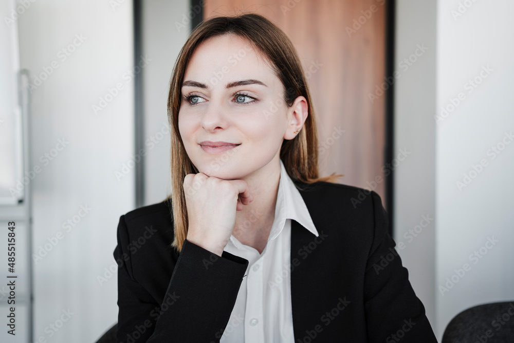 Contemplative businesswoman with hand on chin in office Contemplative businesswoman with hand on chin in office