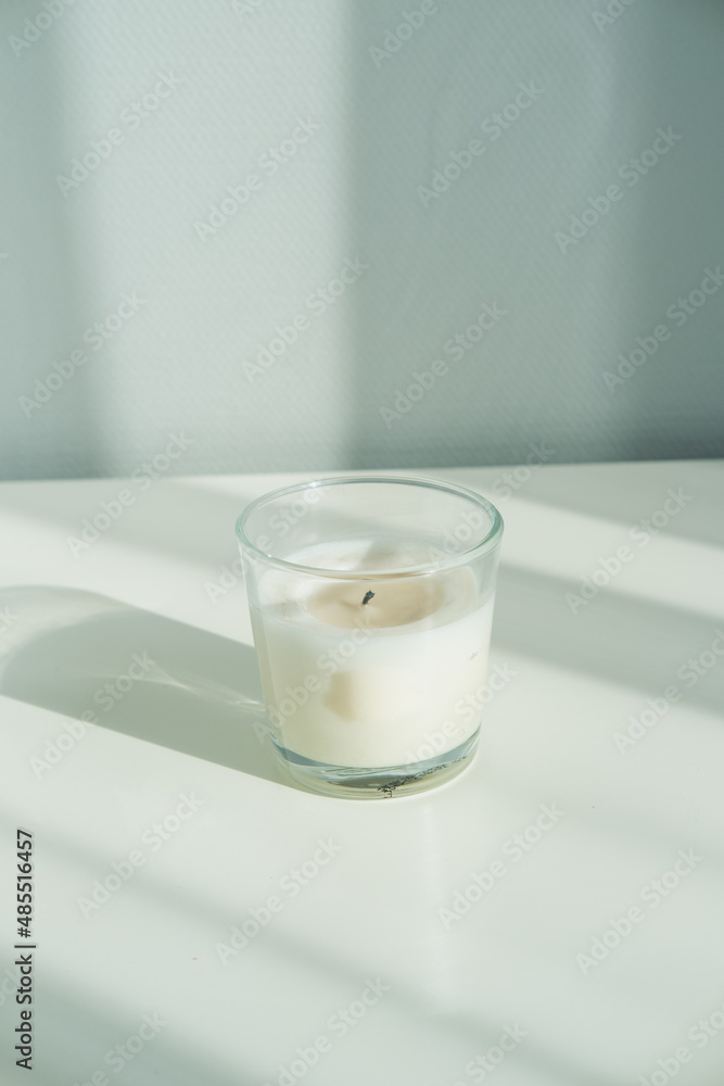 White aroma candle for spa in a bottle on a white table. Minimalism.