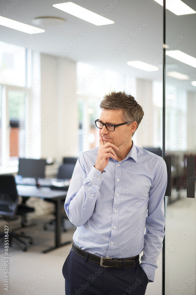 Thoughtful businessman with hand on chin at modern office Thoughtful businessman with hand on chin at modern office