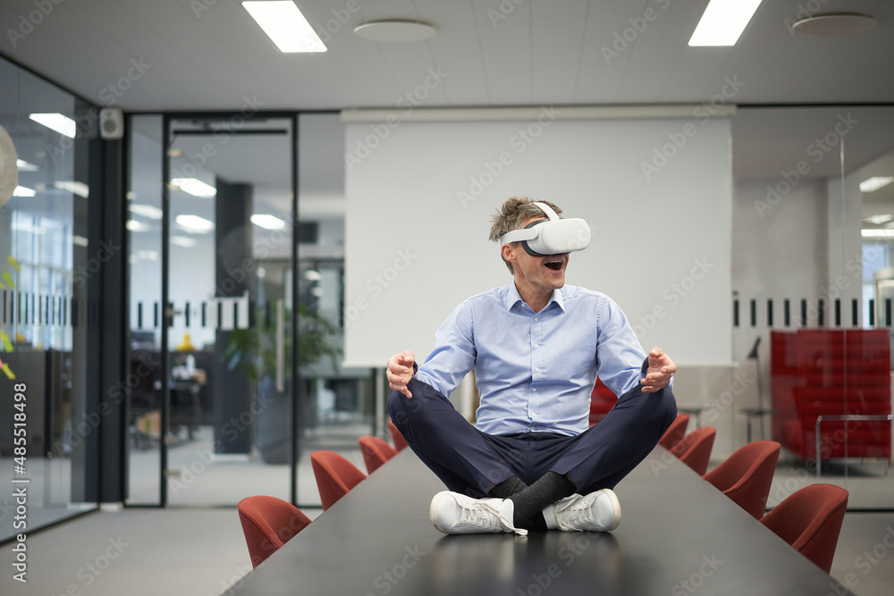 © Westend61 - Businessman wearing VR glasses in meeting room at modern office