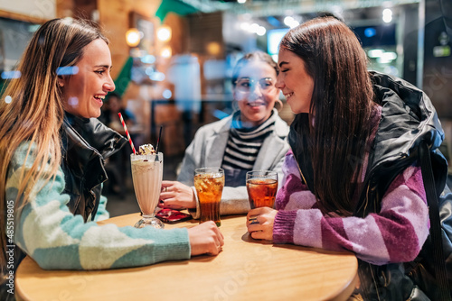 Young women with drinks on table talking in cafe