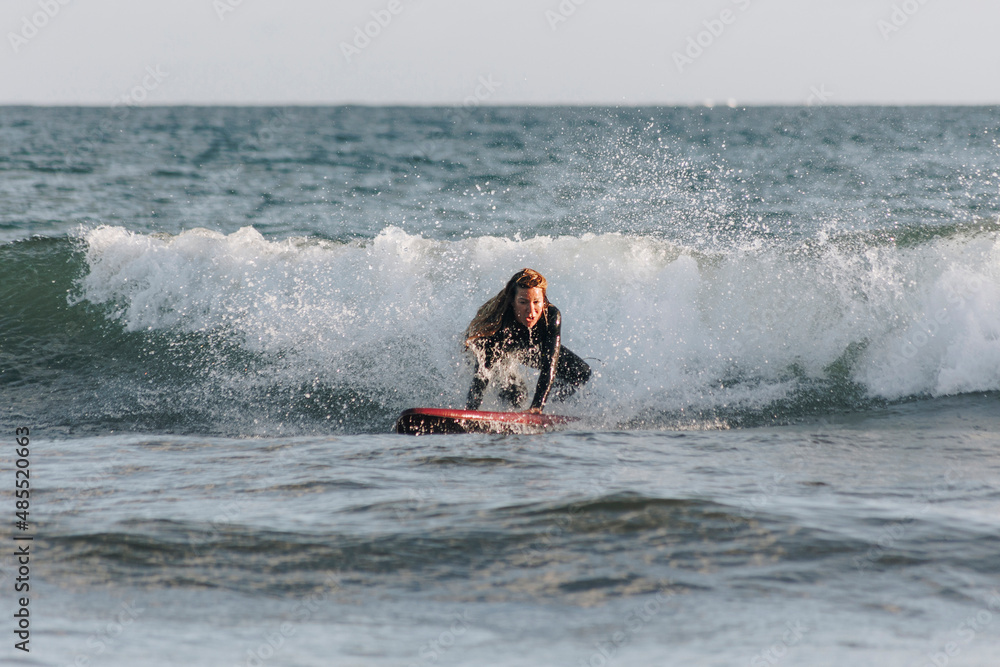 Determined woman surfing in front of wave in sea, Gran Canaria, Canary Islands Determined woman surfing in front of wave in sea, Gran Canaria, Canary Islands