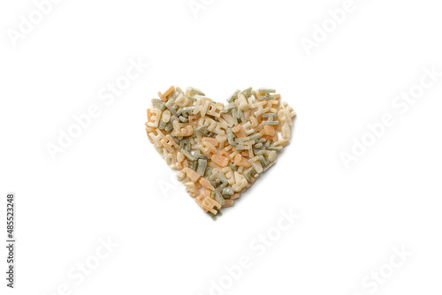 Pasta with the shape of letters stacked in the form of a heart on a white isolated background, top view.