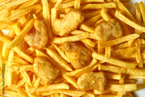 Close-up on the chicken nuggets from above. The nuggets lie on top of the fries