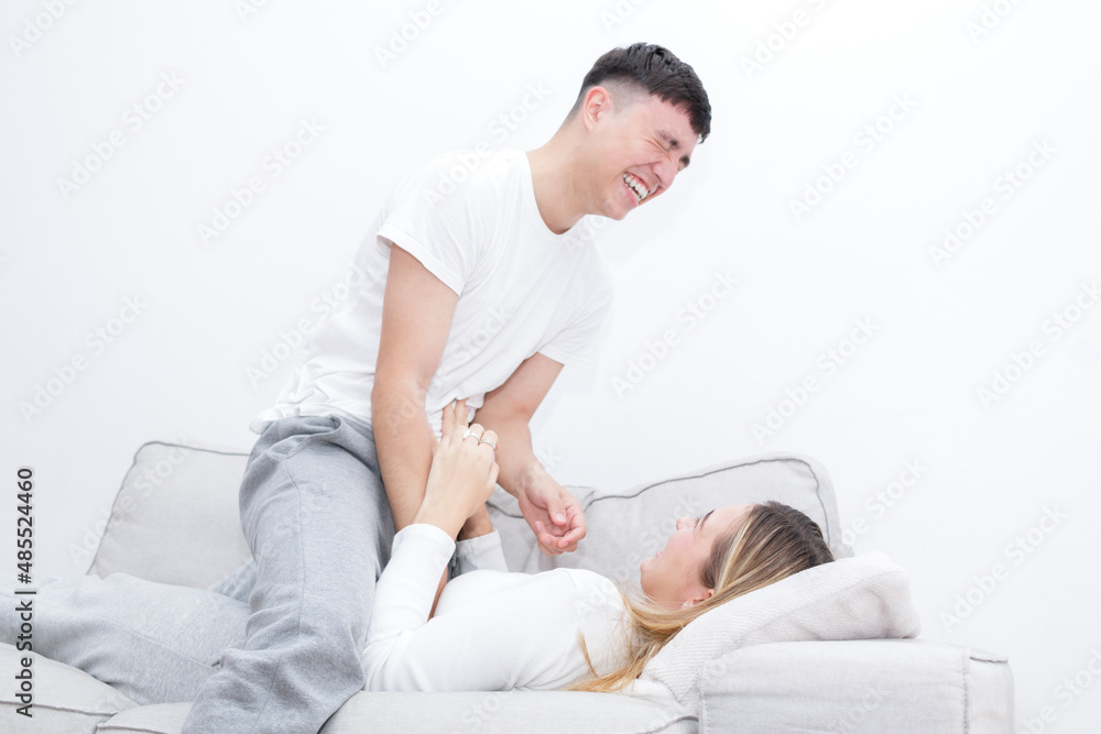 Boyfriend and girlfriend tickling in the sofa. Boy on top of girl. Young couple at home. Heterosexual 18-20 years old couple. Boyfriend and girlfriend tickling in the sofa. Boy on top of girl. Young couple at home. Heterosexual 18-20 years old couple.