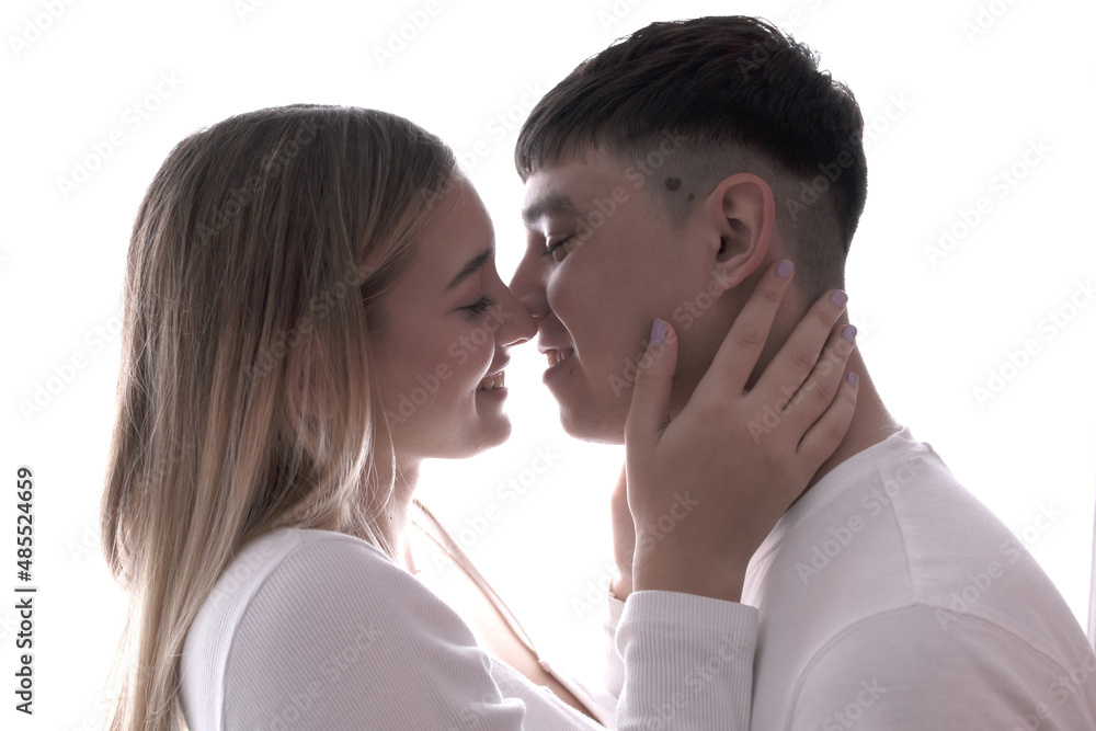 Boyfriend and girlfriend face to face looking at each other at backlight.  Young couple at home. Heterosexual 18-20 years old couple.