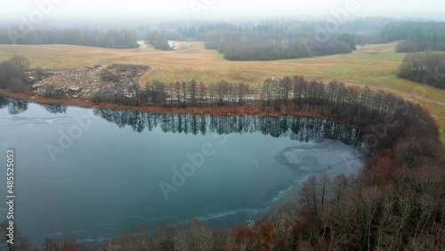 Drone aerial flight over the frozen lake in the winter forest through the fog