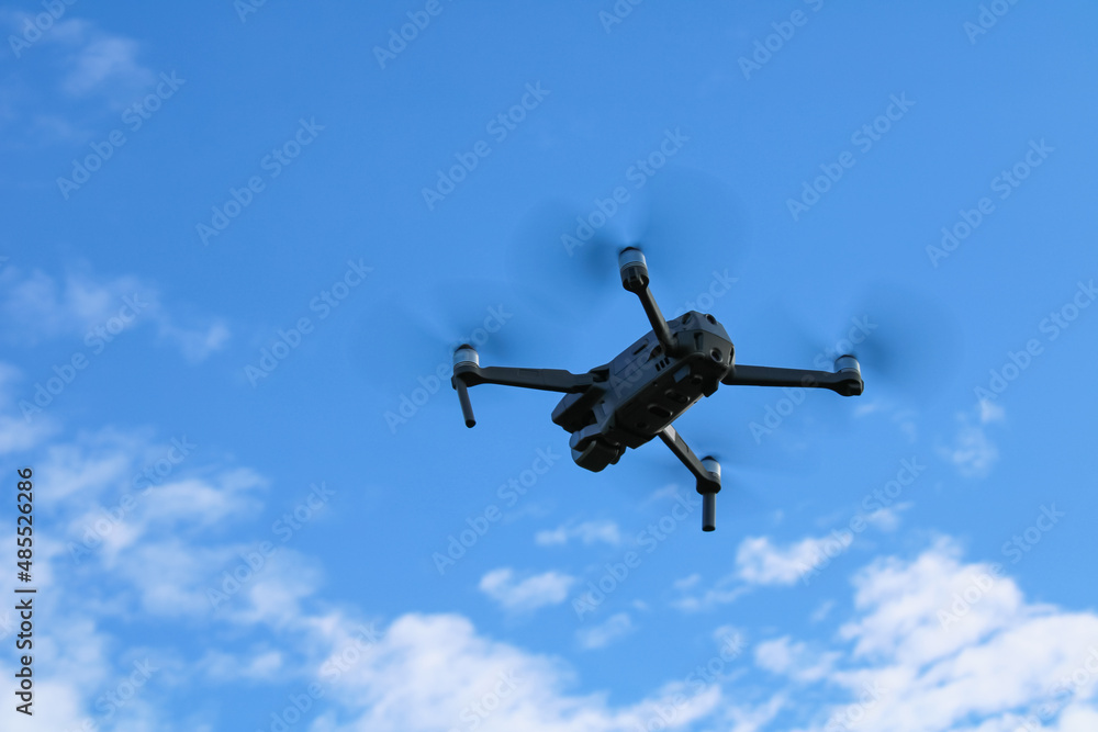 quadcopter drone flying by on the background of blue sky with clouds view from below quadcopter drone flying by on the background of blue sky with clouds view from below