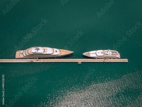 Top view of the luxurious white yachts moored at the long thin quay, blue sea in a sunny day  millionaire concept. © Semachkovsky 