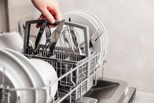 Konstfotografi Close-up of female hand holding full cutlery basket with clean knife, fork, whisk