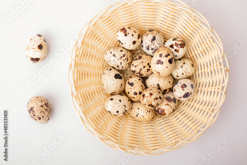 quail eggs in a shell in a basket on a light background