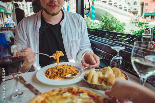 man sitting in cafe eating pasta drinking wine rialto bridge on background venice italy