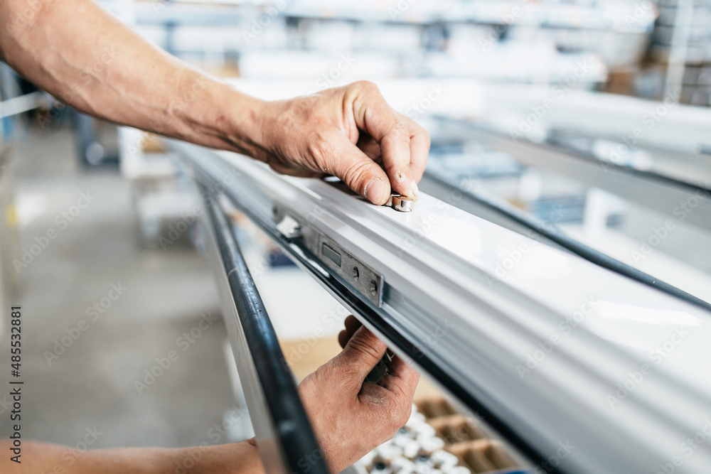 Manual worker assembling PVC doors and windows. Manufacturing jobs
