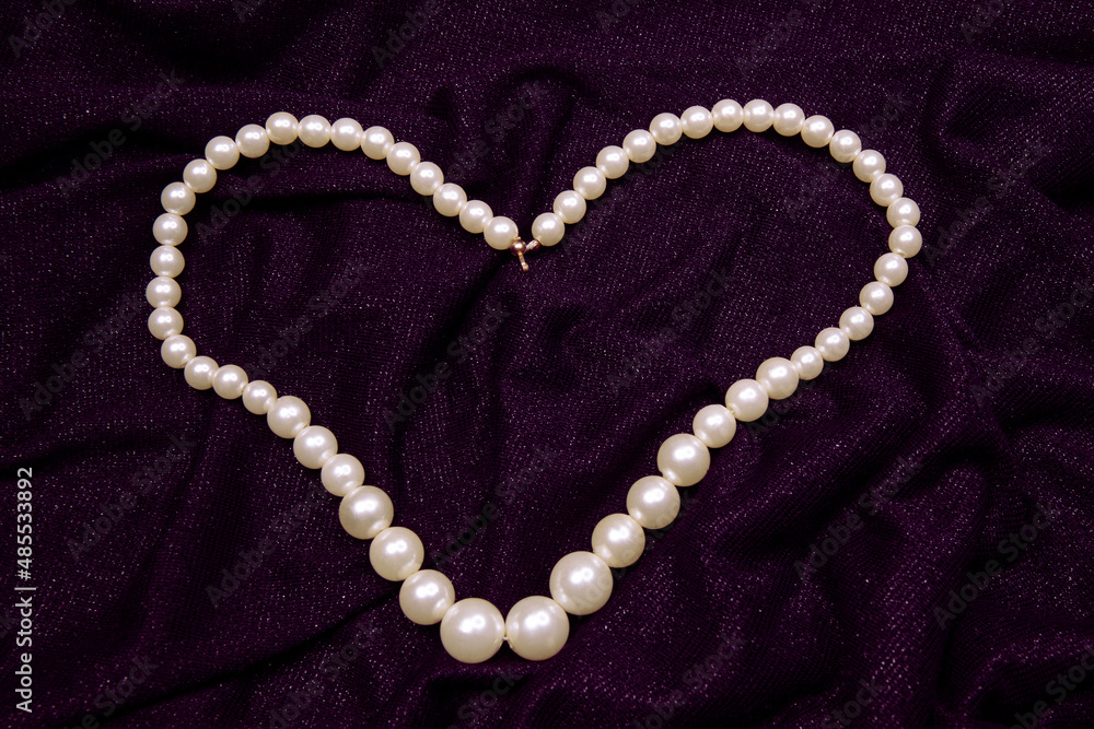 Valentine's Day image with white perl necklace in heart shape on a purple background Valentine's Day image with white perl necklace in heart shape on a purple background