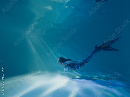 Woman with mermaid tail swims and dives underwater. photo