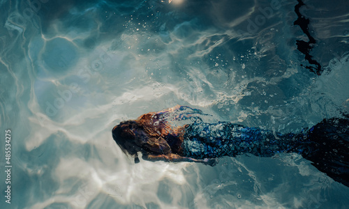 Fotografie Woman with mermaid tail swims and dives underwater.