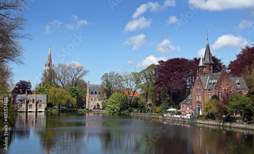 El lago Minnewater en Minnewaterpark, Brujas, Bélgica. A orillas del lago se encuentra el Invernadero y al fondo la torre de la Iglesia de Nuestra Señora.