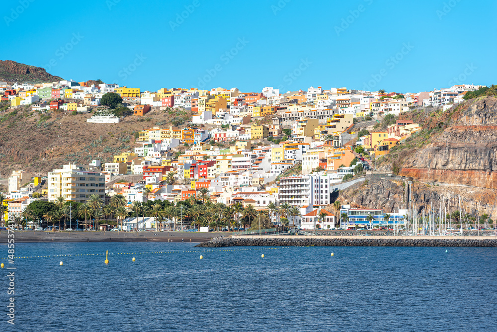 View from sea to San Sebastian de La Gomera. The colorful houses of the capital stretch down the hill to the sea. The Canary archipelago is a popular tourist destination