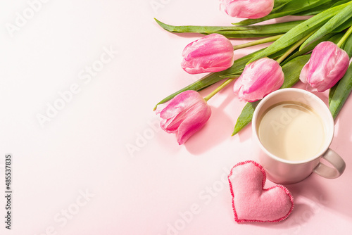 Romantic flat lay composition with a cup of coffee, soft felt hearts, and fresh tulips