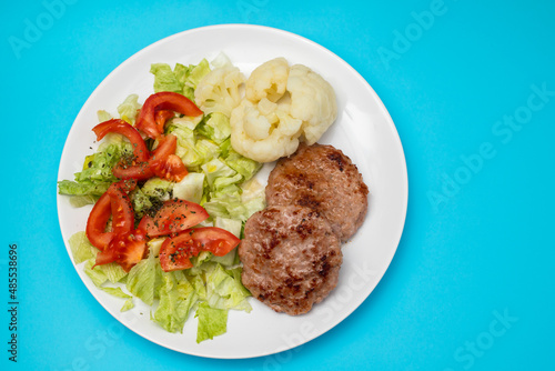ground meat with fresh salad and boiled cauliflower on white plate