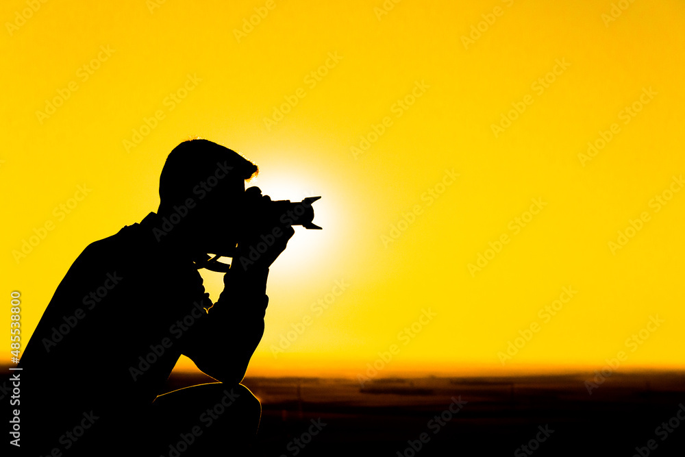 silhouette of a photographer taking a picture at sunset. Copy space for advertising