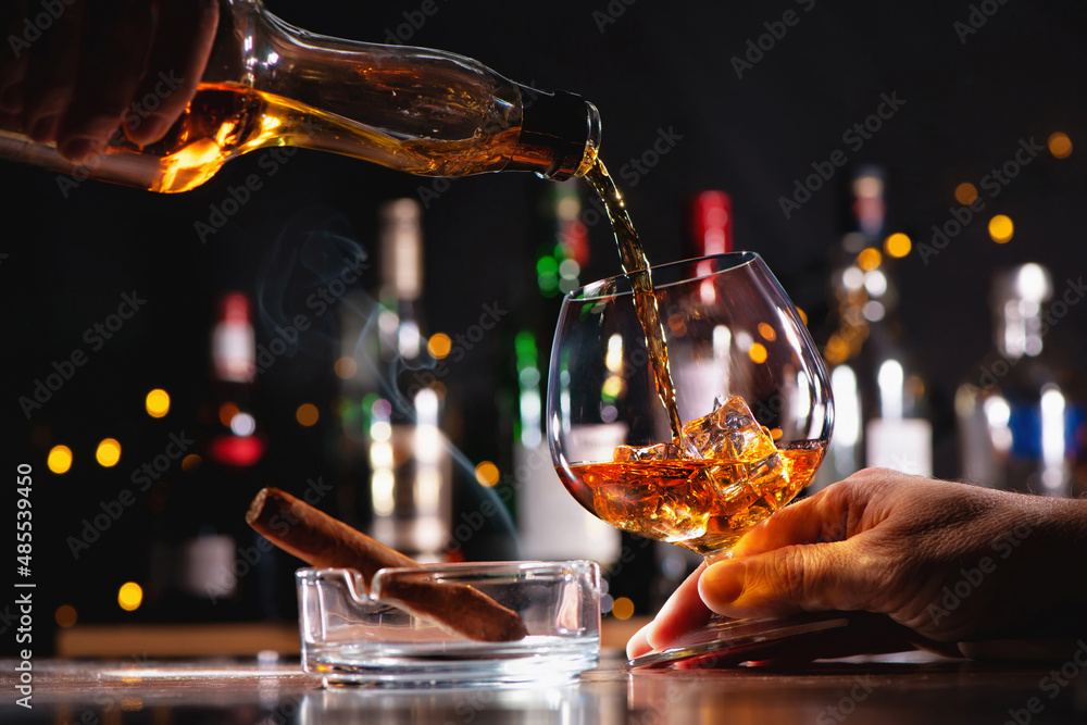 Pouring a whiskey in a glass on bar counter - obrazy, fototapety, plakaty 
