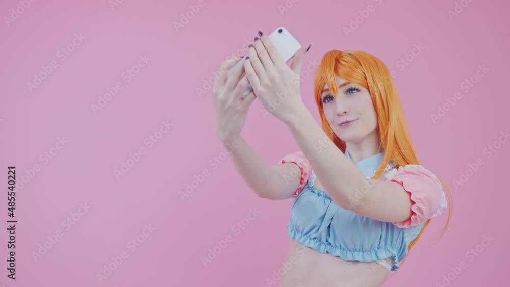 Beginner Caucasian Female Cosplayer Takes Photo Of Herself In A New Ginger Wig medium studio shot pink background. High quality 4k footage Beginner Caucasian Female Cosplayer Takes Photo Of Herself In A New Ginger Wig medium studio shot pink background. High quality 4k footage