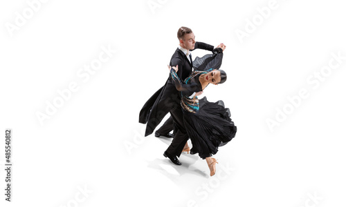 Aerial view of young graceful artistic couple, man and woman dancing waltz isolated over white studio background. Ballroom dances