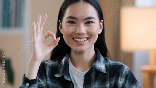 Female portrait happy recommending smiling winner asian woman girl showing ok gesture everything fine sign success good news done consent victory symbol folding fingers zero looking at camera at home photo