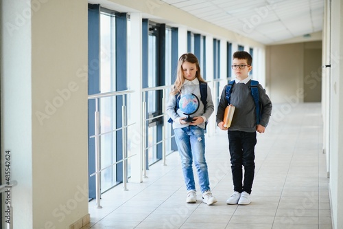 Portrait of smiling school kids in school corridor with books