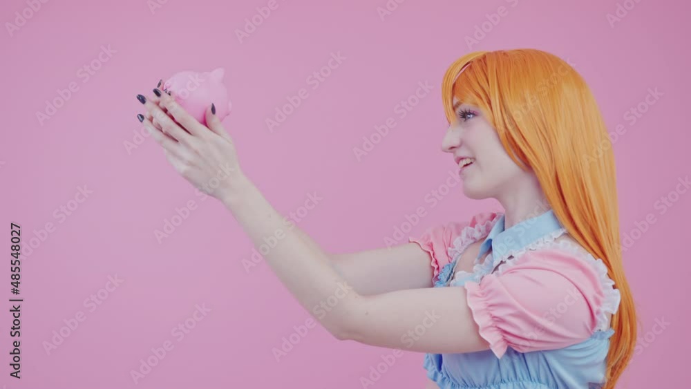 Girlish caucasian woman wishing to save up some money with her new pink piggy bank pink background medium studio shot. High quality 4k footage Girlish caucasian woman wishing to save up some money with her new pink piggy bank pink background medium studio shot. High quality 4k footage