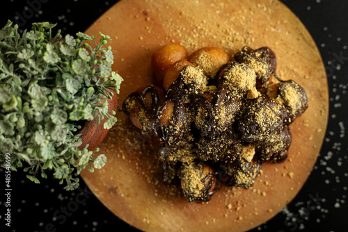 Delicious little chocolate cake sprinkled with crispy waffle slices on dark background