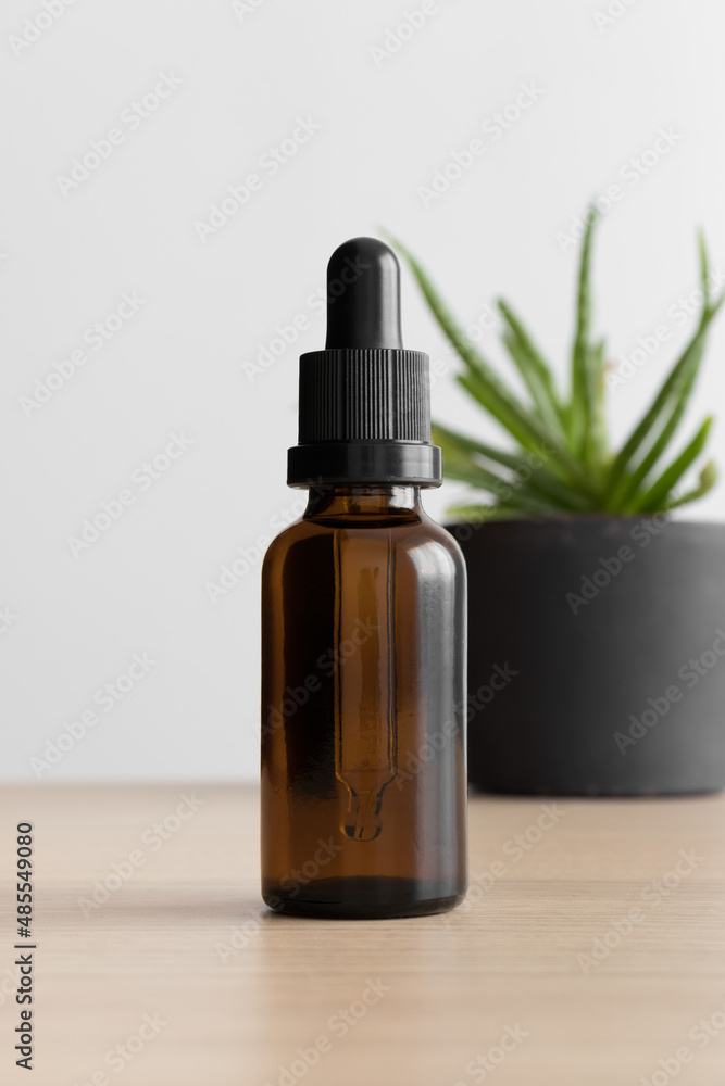 Dropper bottle mockup with a succulent plant on the wooden table. Dropper bottle mockup with a succulent plant on the wooden table.