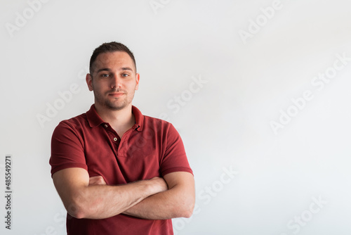 Formal business male portrait. A confident successful casual businessman or manager stands in front of a white background, arms crossed, looking directly at the camera and smiling friendly. High © .shock