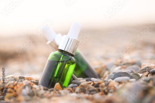 Fototapeta Naklejka Na Ścianę i Meble -  the serum for the face in a green bottle stands on the sand near the sea
