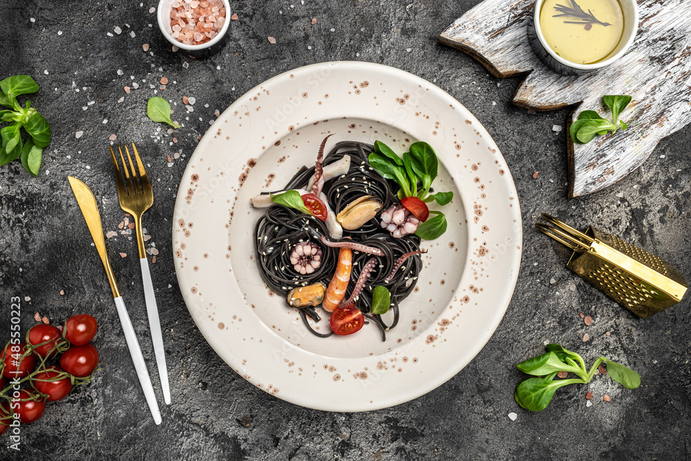 Squid ink spaghetti with seafood octopus, mussels and shrimps on dark background. Restaurant menu, dieting, cookbook recipe top view