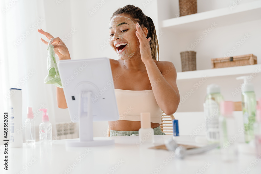 Young black woman with cosmetic mask looking in mirror Young black woman with cosmetic mask looking in mirror