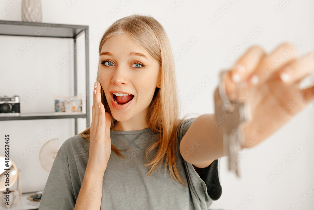 The girl looks surprised and happy because she received the keys from her new apartment. The girl is busy with the unpacking of all her things. Concept of moving The girl looks surprised and happy because she received the keys from her new apartment. The girl is busy with the unpacking of all her things. Concept of moving