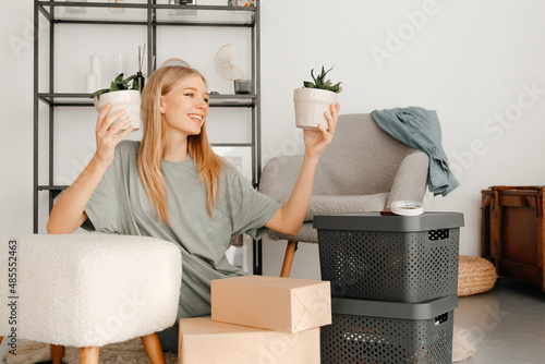 Beautiful girl is thinking how to arrange all her things in the new apartment. Young woman is smiling and looks happy. Concept of moving