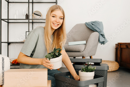 Nice-looking young woman is packing the stuff in the boxes. The girl is preparing to move into other apartment. Concept of moving